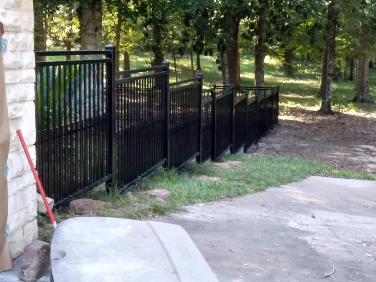 Barda de hierro negro instalada de forma escalonada (stepped) para adaptarse a la pendiente del terreno.
