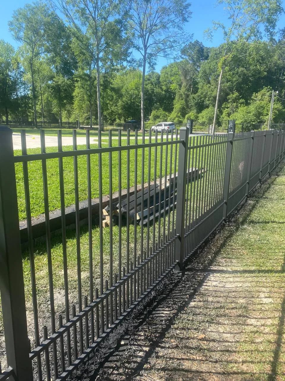 Otra perspectiva de la misma barda larga del perro (file_26), mostrando la extensión de la propiedad hacia el fondo, conectando con pilares de piedra y el portón principal a lo lejos.