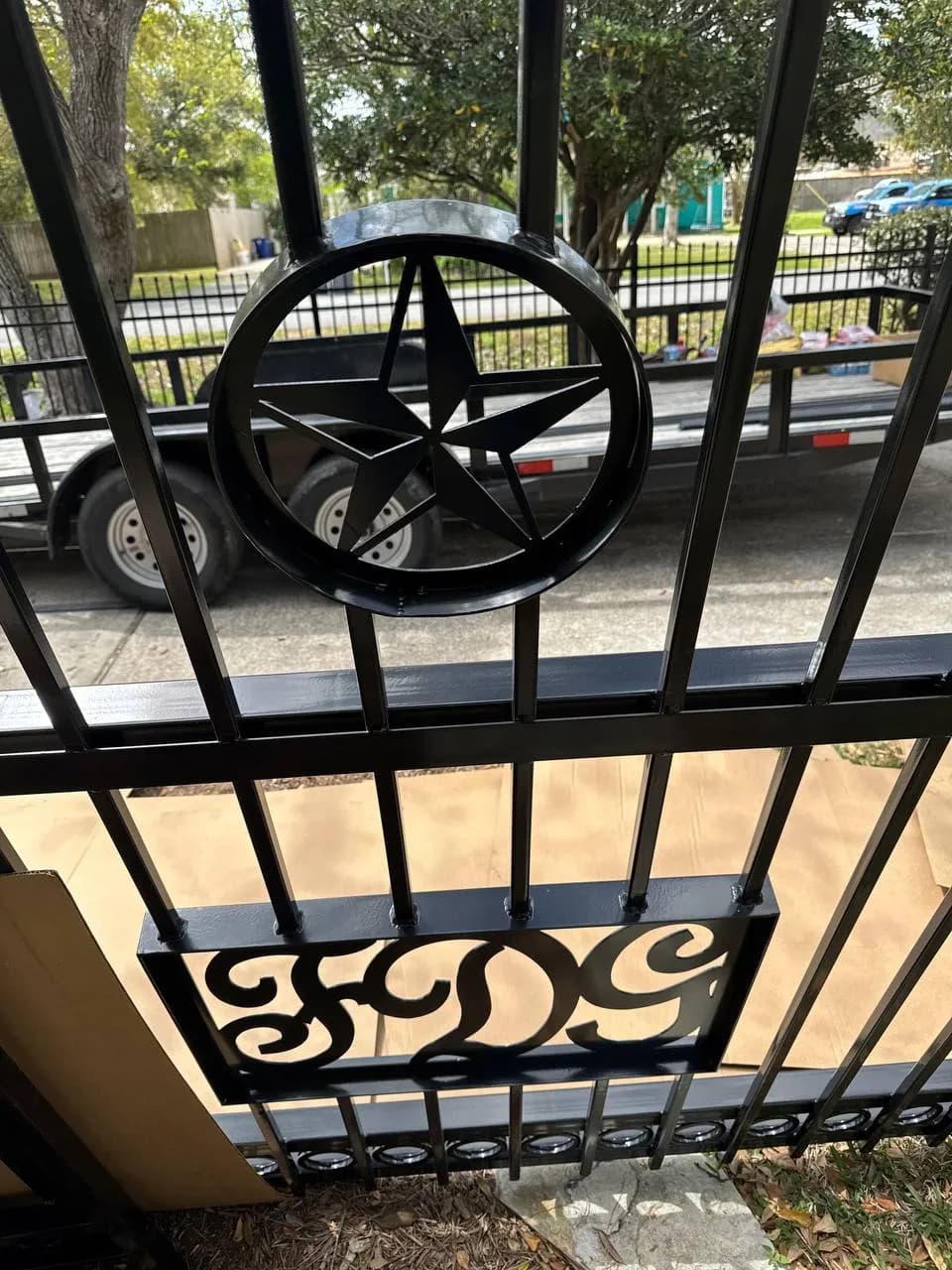 Close-up al detalle central de un portón: Estrella tipo Texas calada en un círculo de placa metálica, con las iniciales 'FDG' debajo, hechas en corte láser con tipografía estilo western/vintage.