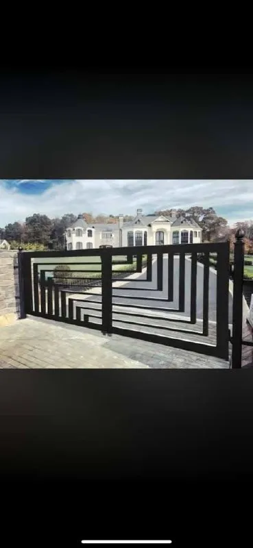 Impresionante portón deslizante con un patrón geométrico en zigzag/laberinto asimétrico en la parte inferior de los paneles. Muy moderno, tipo Art Decó contemporáneo, frente a una mansión de piedra.