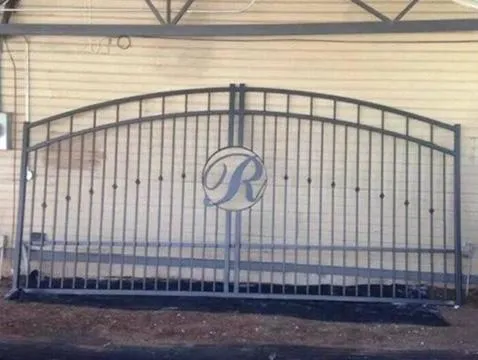 Portón con monograma central 'R' en corte láser, diseño de arco clásico.