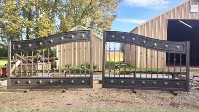 Portón con aplicaciones de estoperoles decorativos y diseño de arco doble.